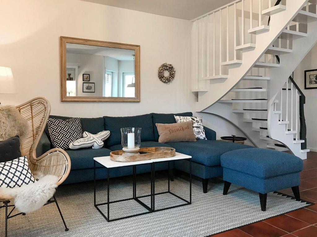 sala de estar con sofá azul y escalera en Holiday Home Sandmuschel by Interhome en Norddeich