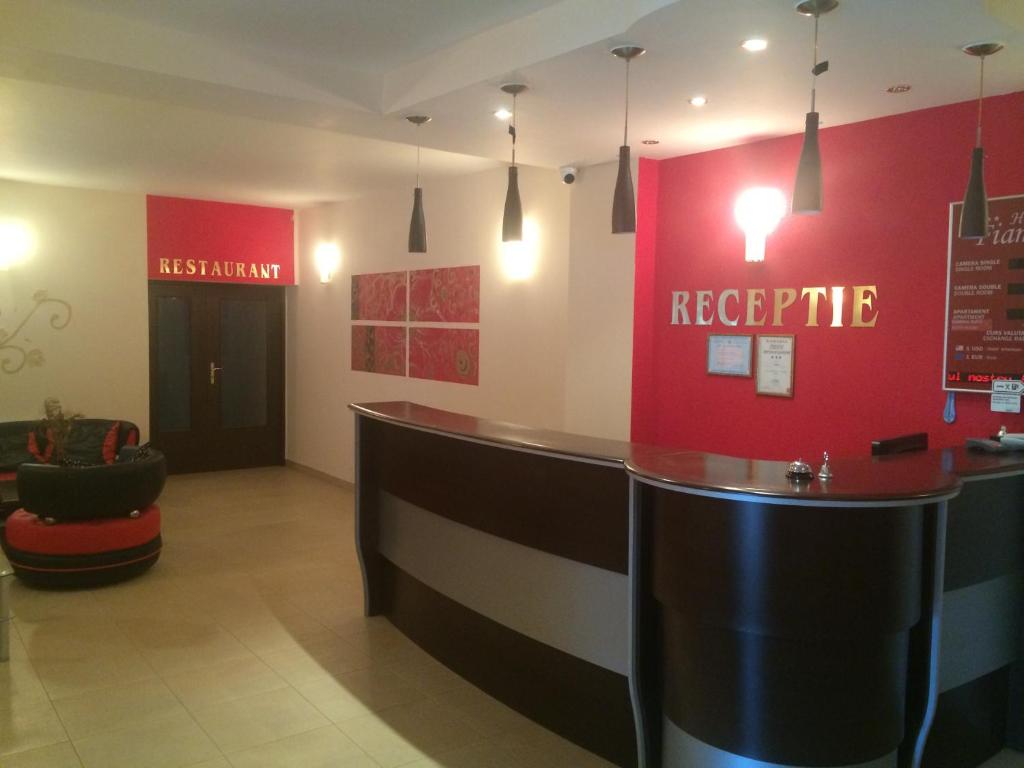 a hotel lobby with a reception desk and a red wall at Hotel Fiama in Oţelu Roşu