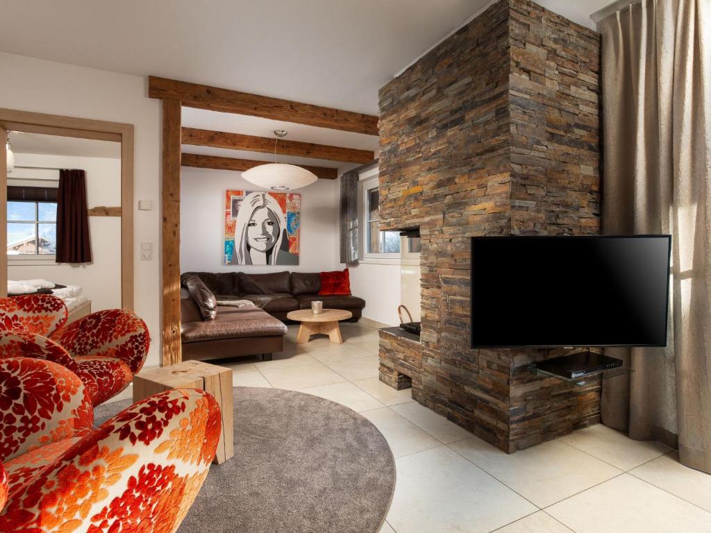 sala de estar con pared de piedra y TV de pantalla plana. en Apartment Mountain Resort C15 by Interhome, en Kaprun