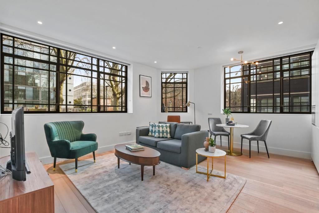Hotel Whitfield Street Residences by Aeria Apartments, a living room with a couch and chairs and windows at Whitfield Street Residences by Aeria Apartments in London