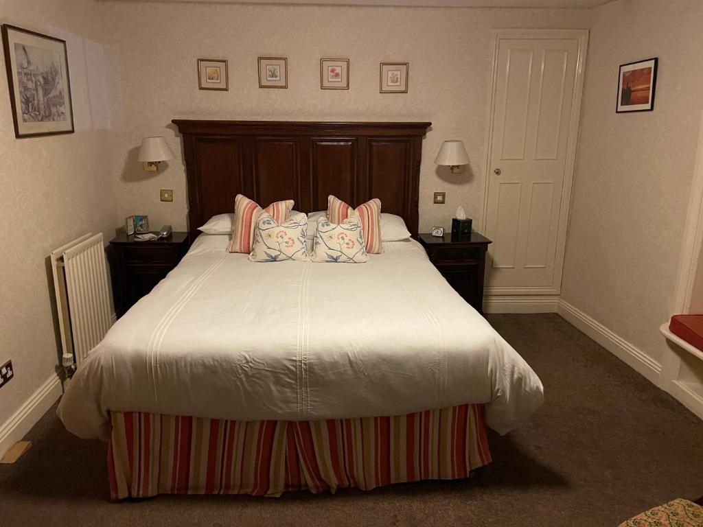 a bedroom with a large bed with pink pillows at The Olde Ship Inn in Seahouses