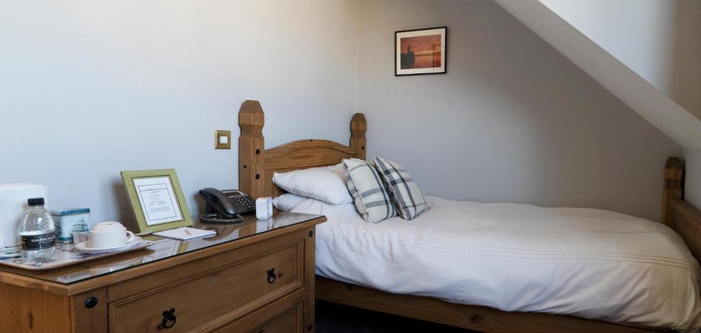 a bedroom with a bed with a wooden head board at The Olde Ship Inn in Seahouses