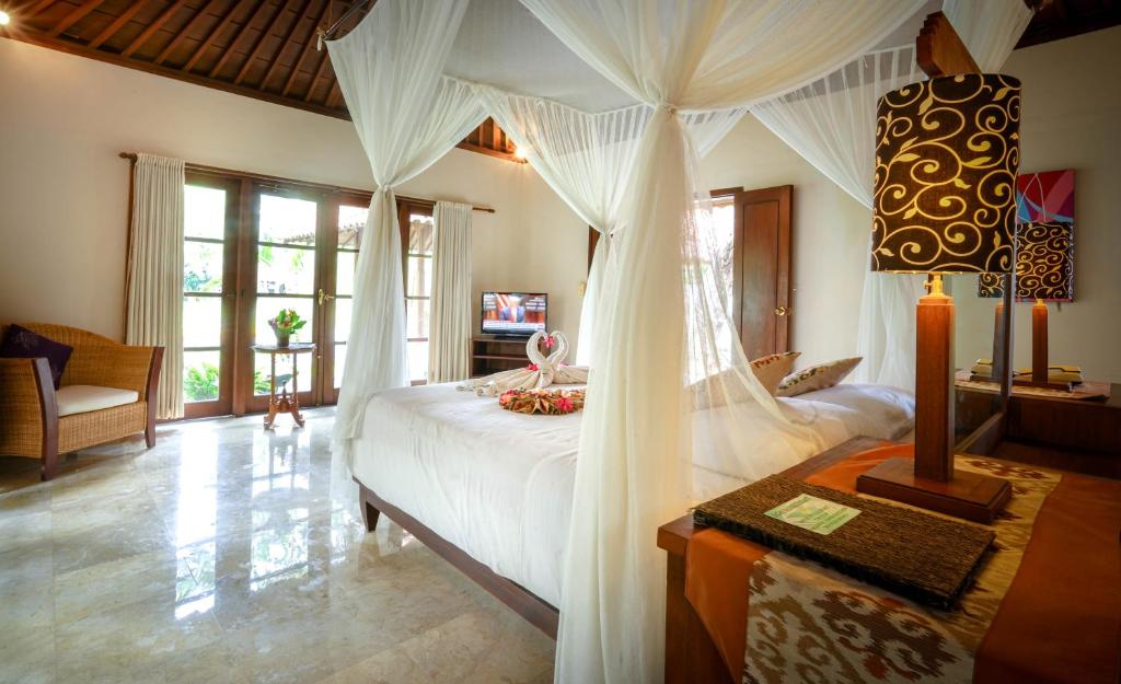 1 dormitorio con 1 cama grande con dosel en Natah Bale Villas, en Sanur