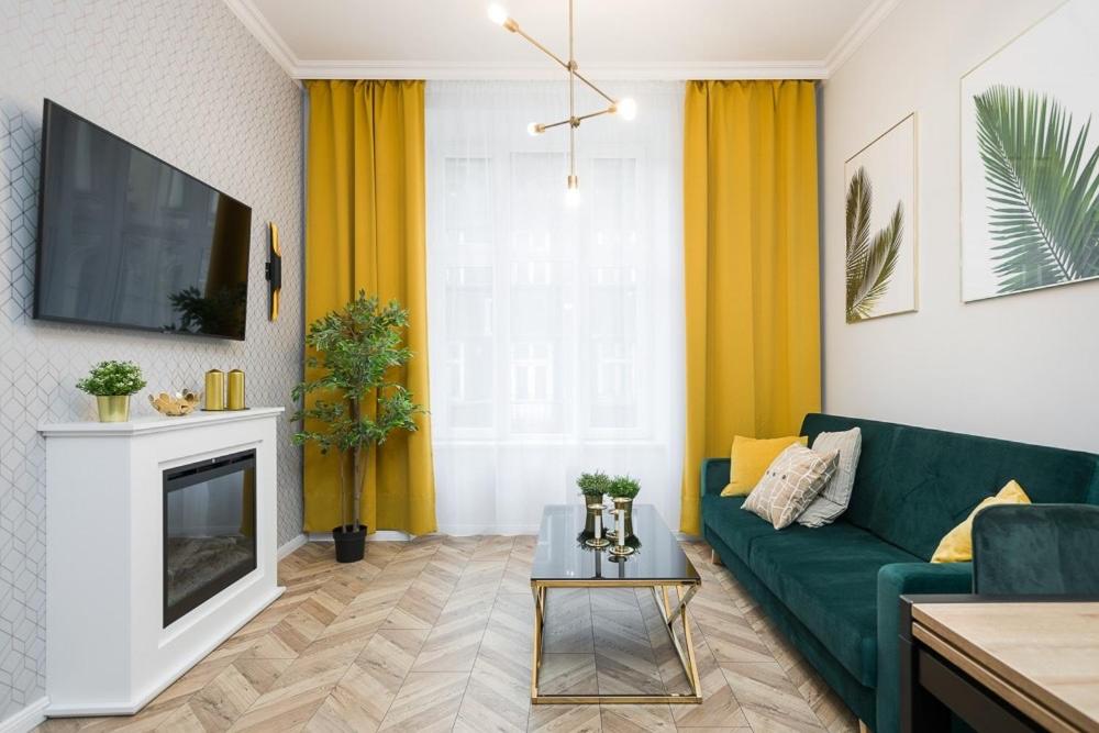a living room with a green couch and a fireplace at Glamorous Apartment Old Town Cracow in Kraków