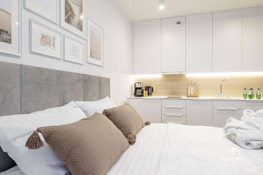 a bedroom with a bed and a kitchen with white cabinets at Apartament Baltic Dune - Pinea Apartments Pobierowo in Pobierowo