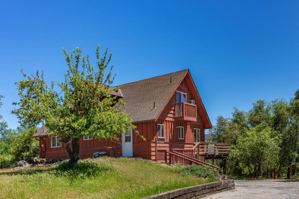a red house on a hill with a tree at Hodges Hill Yosemite House in Oakhurst