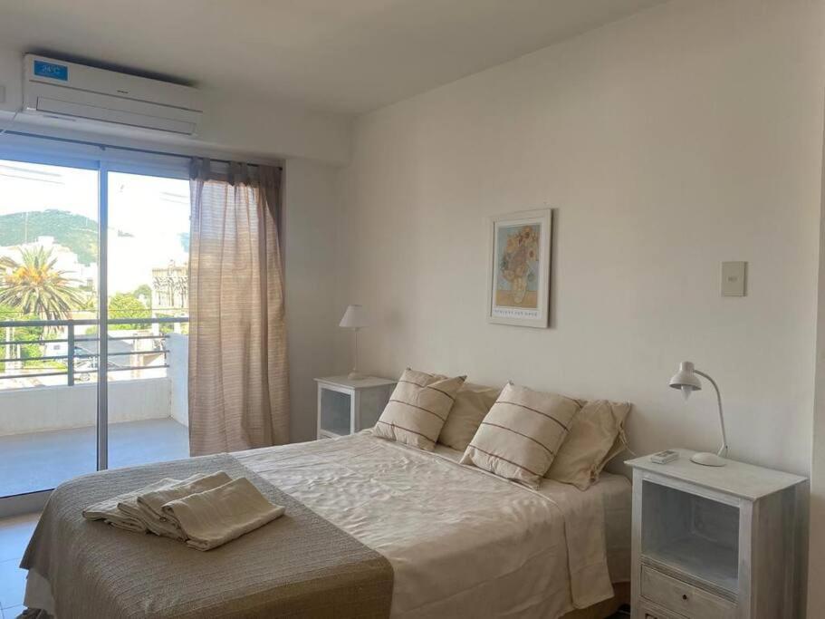 a white bedroom with a bed and a balcony at Departamento tranquilo completamente equipado in Salta