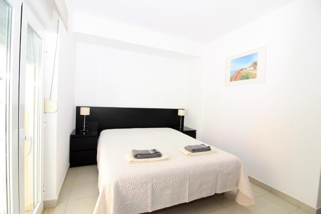 een witte slaapkamer met een bed met twee handdoeken erop bij Historic Centre A - Albufeira in Albufeira