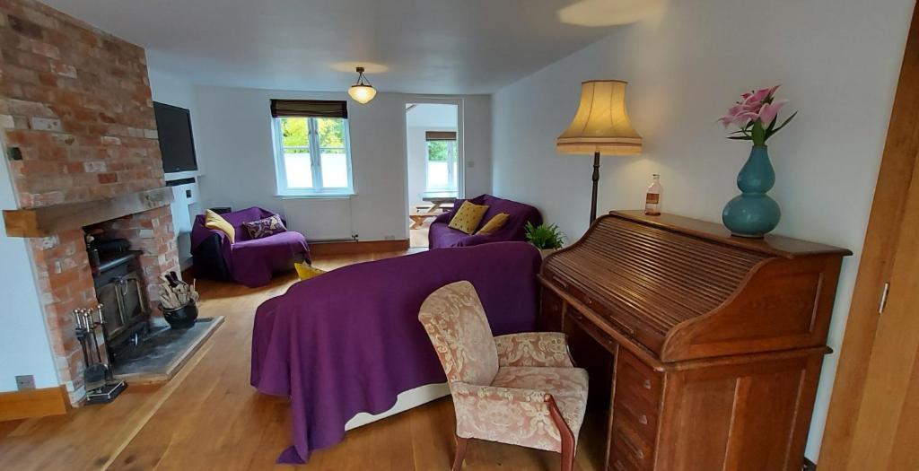 a living room with a purple bed and a piano at Tor Cottage, perfectly positioned! in Glastonbury