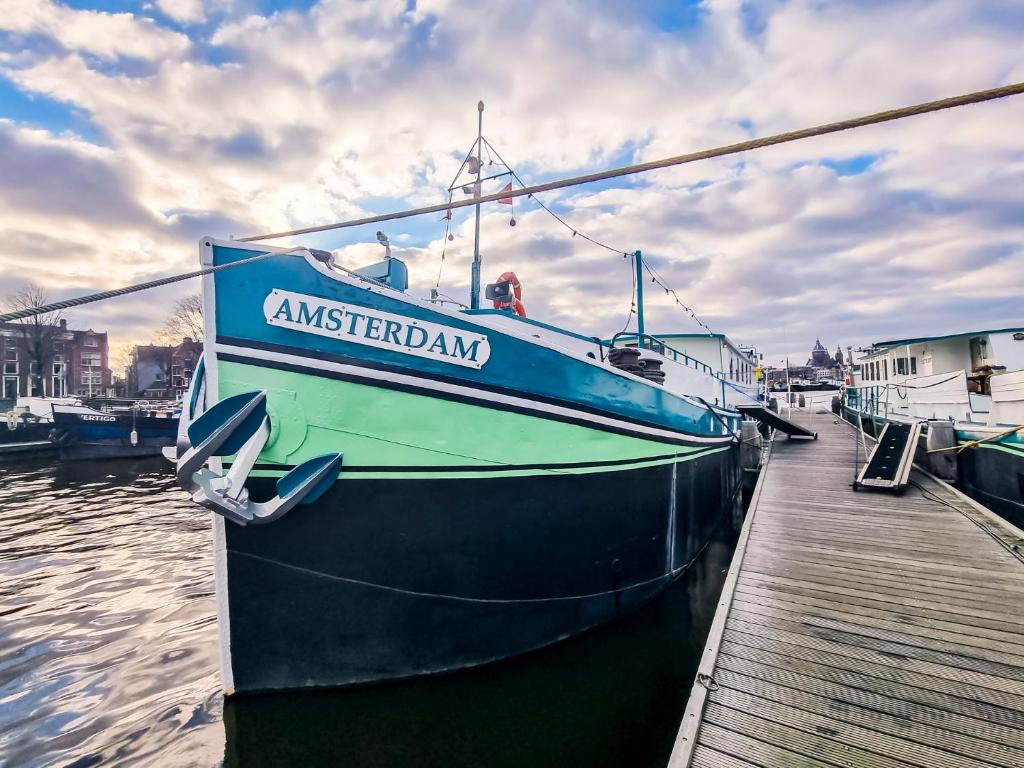 een blauwe boot is aangemeerd bij een dok bij Amsterdam Hotelboat in Amsterdam