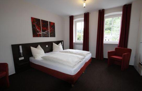 a bedroom with a bed and a red chair at Altes Pfarrhaus 