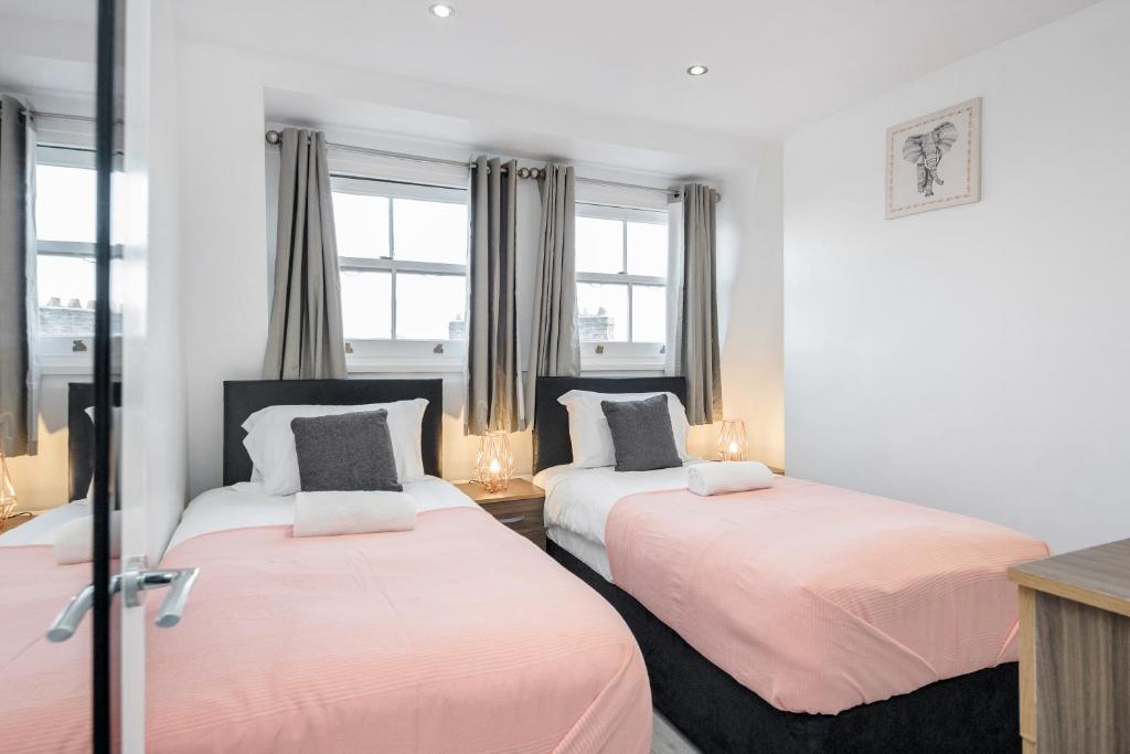 dwa łóżka w pokoju z dwoma oknami w obiekcie Cosy and Functional 1 bedroom flat in London w Londynie