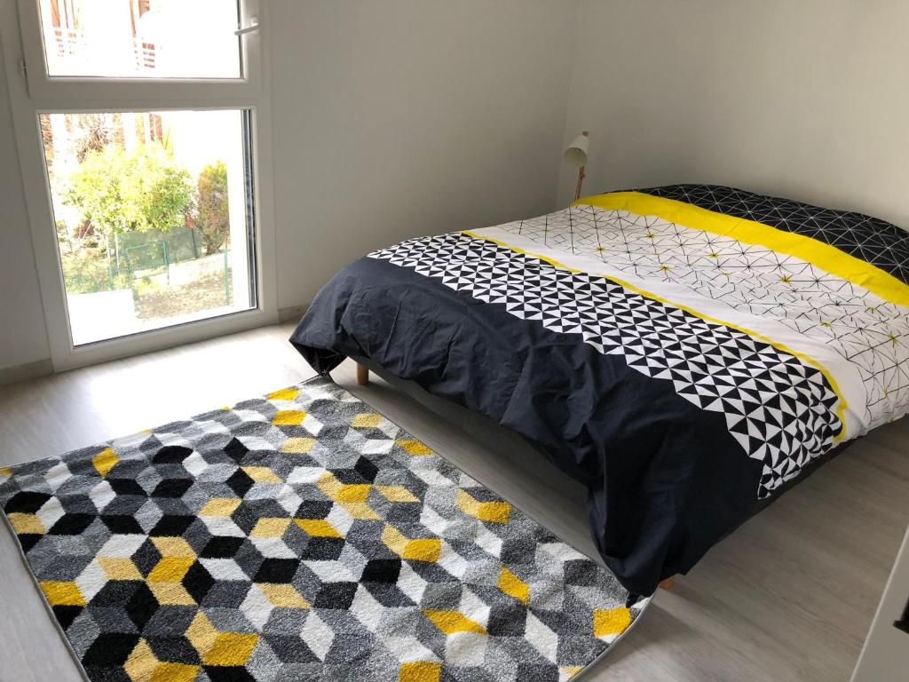 een slaapkamer met een bed en een tapijt op de vloer bij Résidence Neuve entre montagne et lac in Aix-les-Bains
