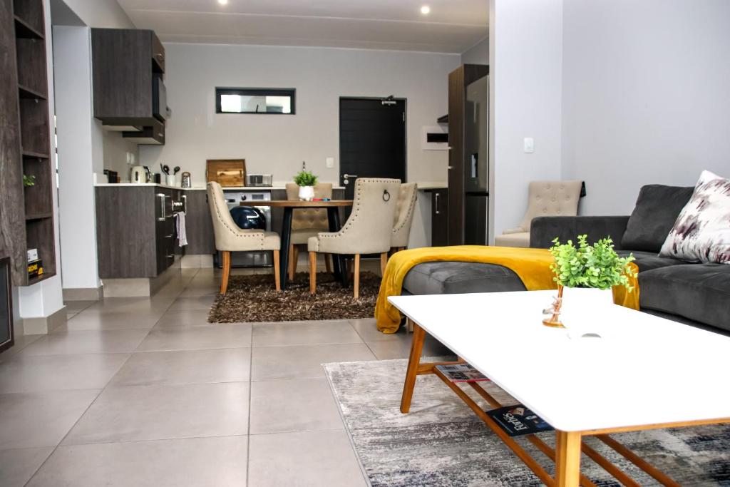 uma sala de estar com um sofá e uma mesa em “Pop Inn” modern apartment in heart of Bryanston em Joanesburgo