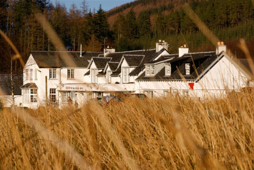 ein großes weißes Haus mit schwarzen Dächern und hohen Grasflächen in der Unterkunft MHOR 84 in Kingshouse