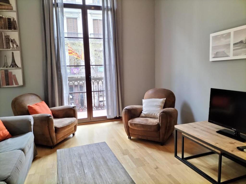 salon z 2 krzesłami i telewizorem w obiekcie Anais Apartments by gaiarooms w Barcelonie
