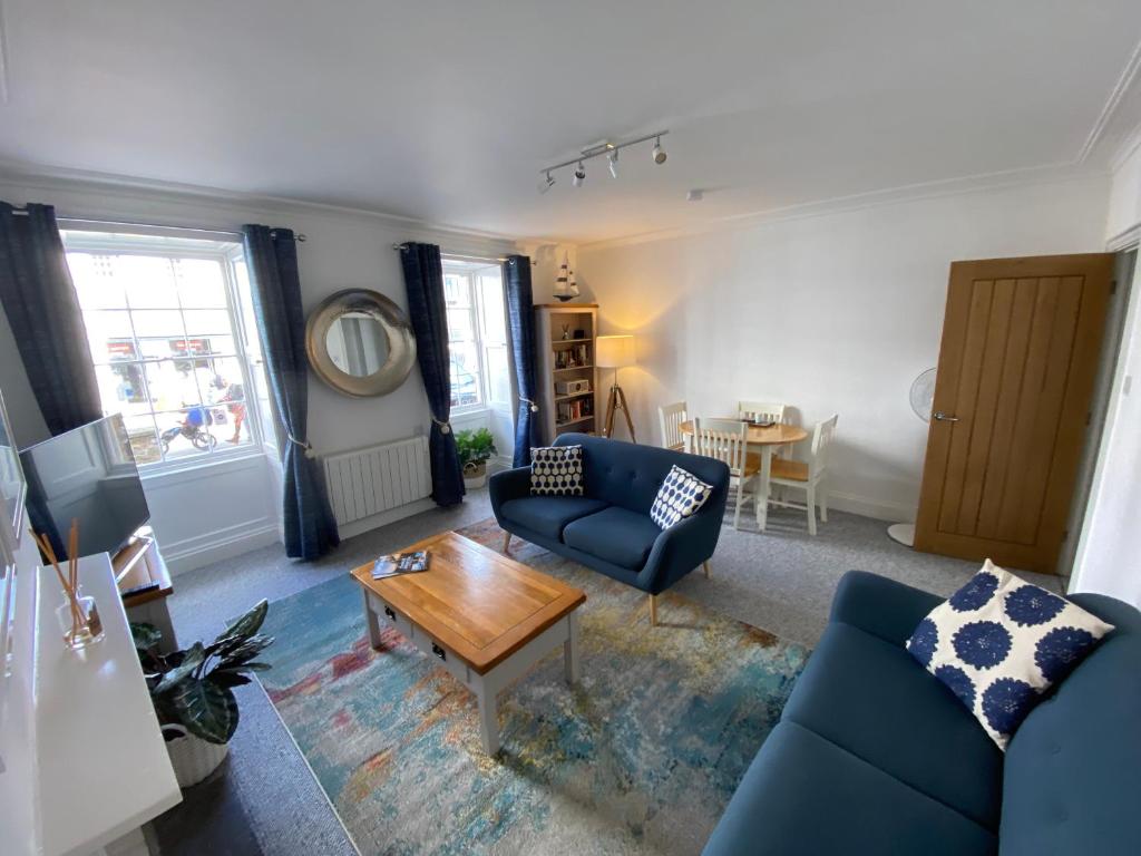 a living room with a blue couch and a table at Bank Place in Falmouth