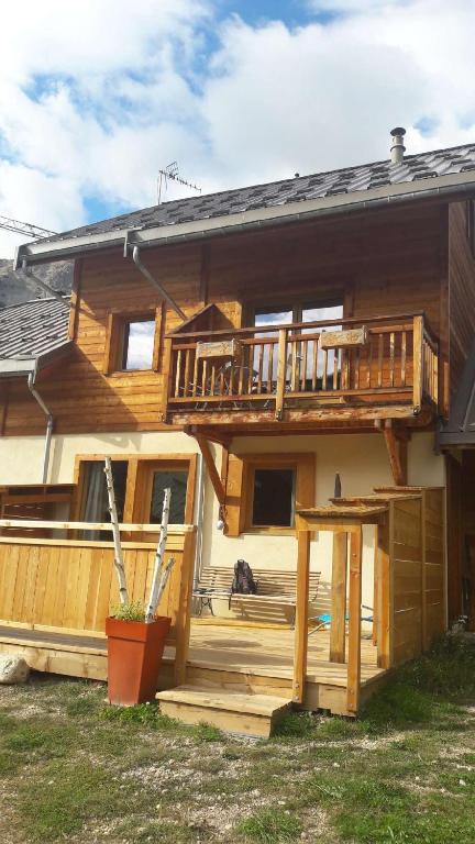 a log cabin with a deck and a house at Le Chalet de Lili in Névache