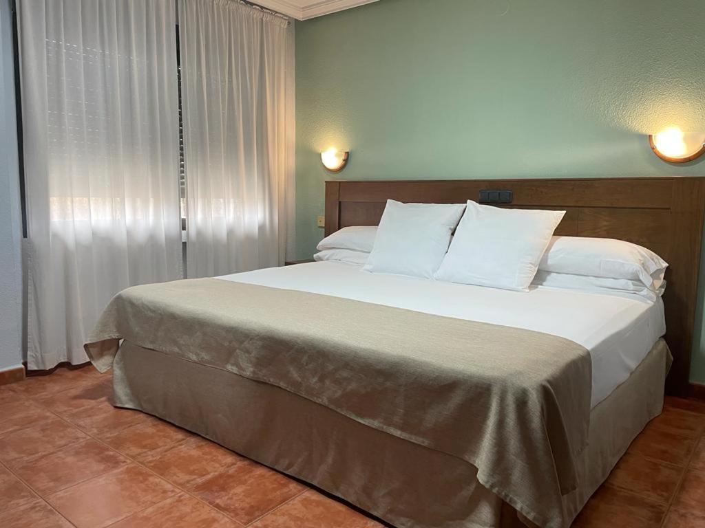 1 dormitorio con 1 cama grande con almohadas blancas en Hotel Los Kekes, en Coria
