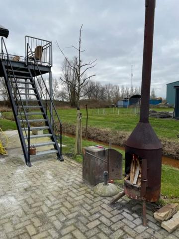 a brick patio with a stove and a staircase at Onder de pannen in Stavoren