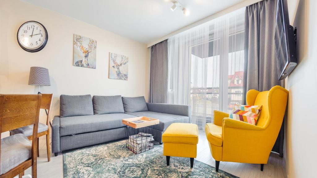 ein Wohnzimmer mit einem blauen Sofa und gelben Stühlen in der Unterkunft Apartamenty Sun & Snow Bursztynowa in Kąty Rybackie
