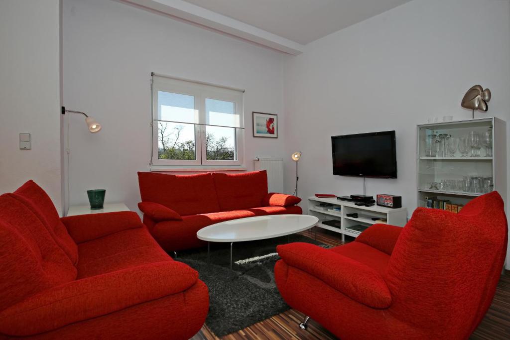 a living room with red chairs and a tv at Macoma Baltica Wohnung 03 in Kühlungsborn