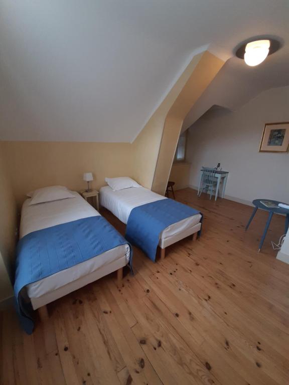 2 camas num quarto com pisos em madeira e um sótão em Logis Hôtel Restaurant L'Auberge du Chateau em Muret-le-Château