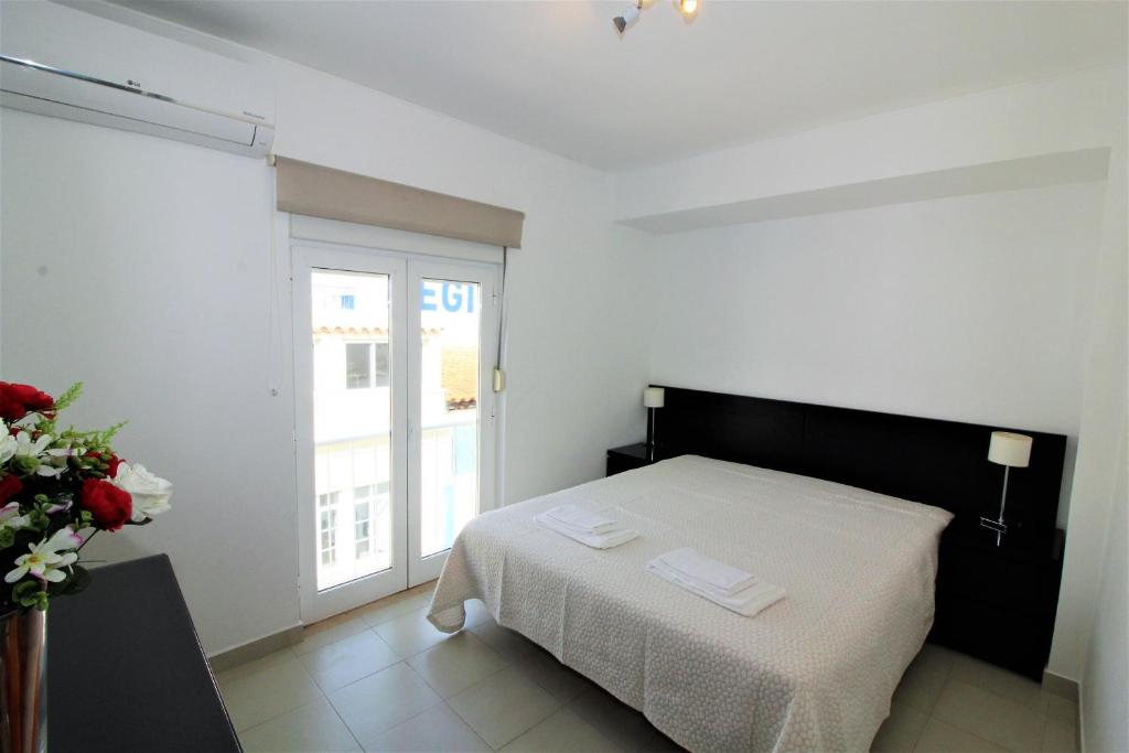 a white bedroom with a bed and a window at Historic Centre C - Albufeira in Albufeira