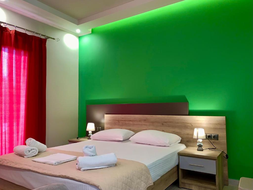 sypialnia z zieloną ścianą i łóżkiem z 2 poduszkami w obiekcie Elia Beach Apartments Vrachos w mieście Loutsa