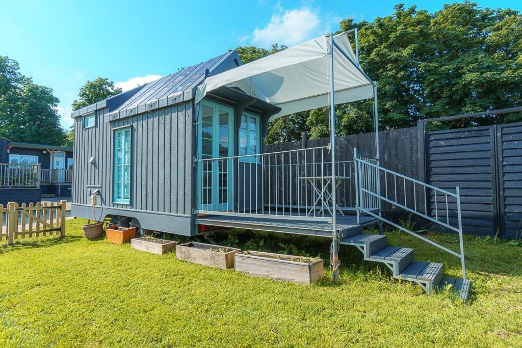 a tiny house with a porch and stairs in a yard at The Shepherd's Hut, Quex Park Estate in Birchington