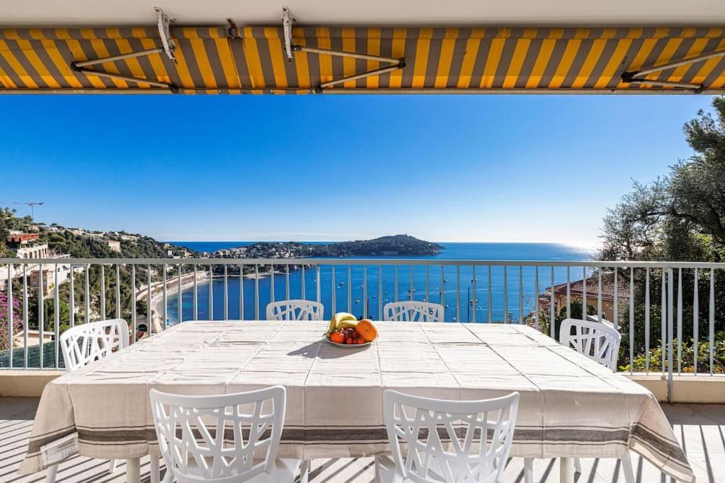 een tafel en stoelen op een balkon met uitzicht op de oceaan bij Villefranche Sur Mer:Appartement-villa, Vue mer, jardin, parking. in Villefranche-sur-Mer