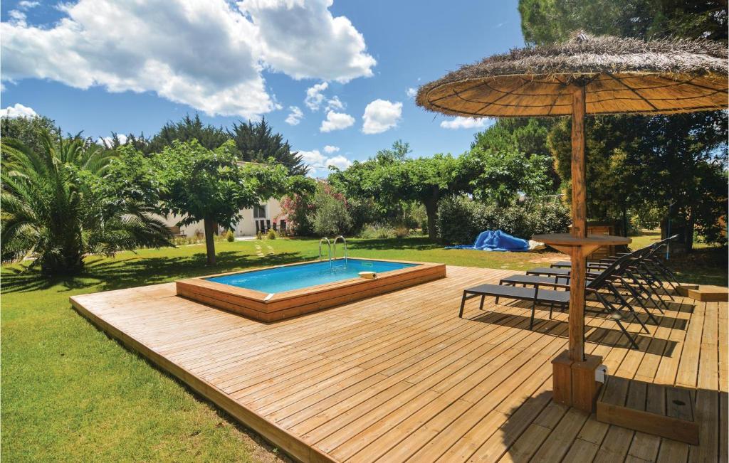 a wooden deck with a swimming pool and an umbrella at 3 Bedroom Stunning Home In Villen,-ls-maguelone in Villeneuve-lès-Maguelonne