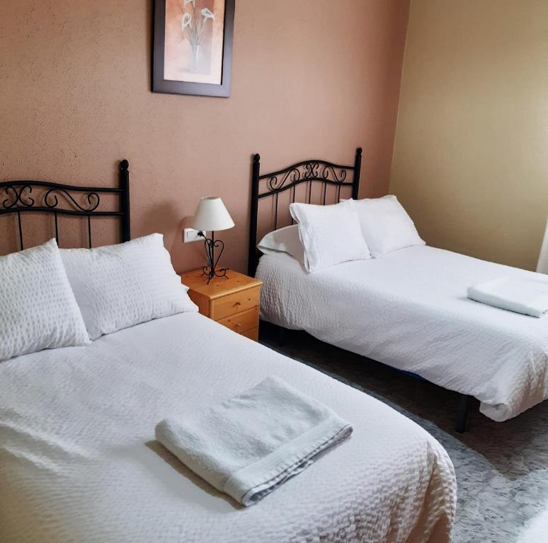 1 dormitorio con 2 camas con sábanas blancas en Alojamiento Mª Carmen, en El Real de la Jara