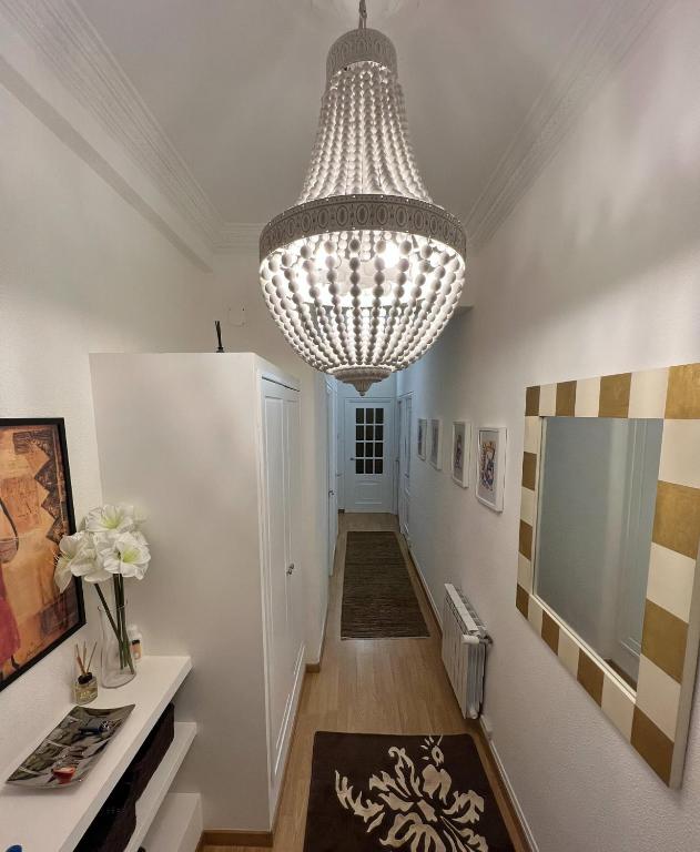a hallway with a large chandelier hanging from a ceiling at Céntrico piso con patio y garaje in A Coruña