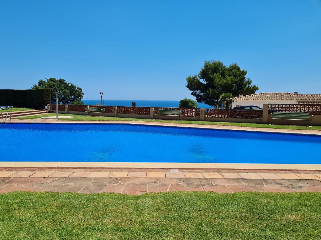 a large blue swimming pool in the grass at S'Agaró Apartment with sea views and pool in Sant Feliu de Guixols