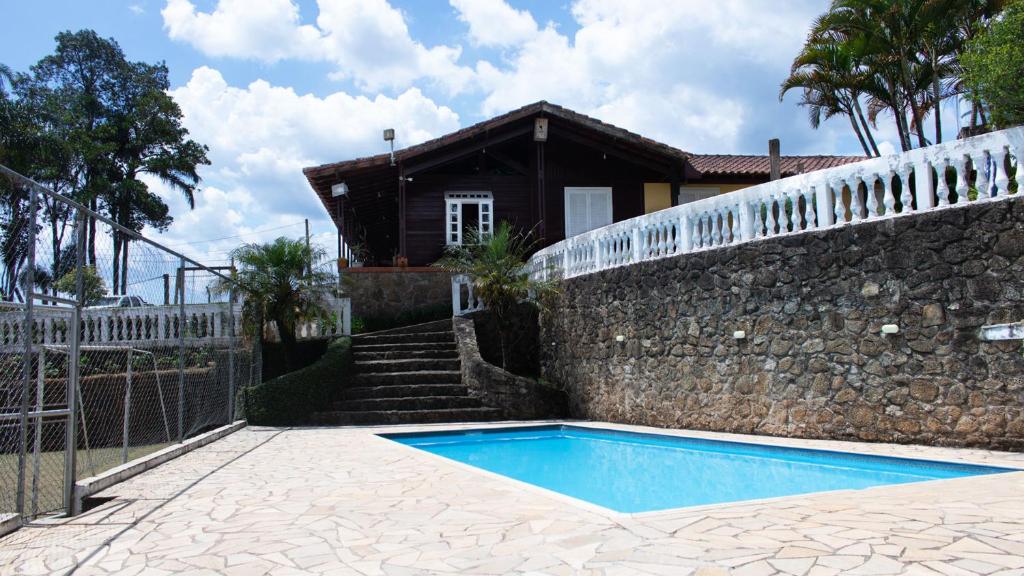 una casa con piscina junto a una pared de piedra en Casa de campo c piscina e churrasq em Mairipora SP, en Mairiporã