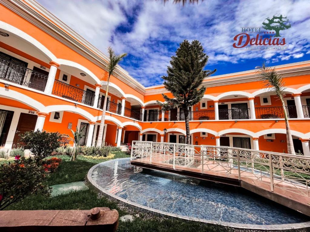 an orange building with a pool in front of it at Hotel Delicias Tequila in Tequila