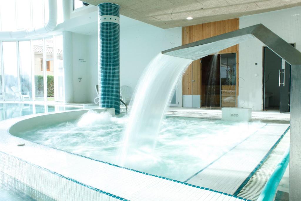 una fuente de agua en una piscina en HOTEL & APARTAMENTS THALASSA Sport & Spa, en Roses