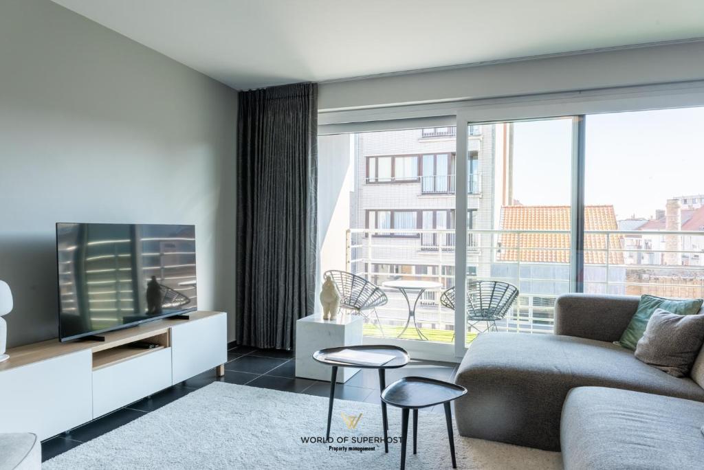 sala de estar con sofá y TV en New modern apartment near the sea and city centre, en Ostende
