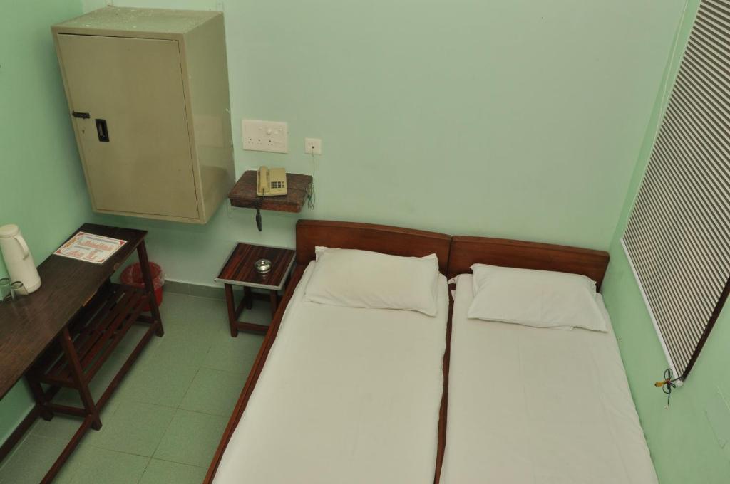 een kleine kamer met een bed en een telefoon bij VALLI HOTEL in Thanjāvūr