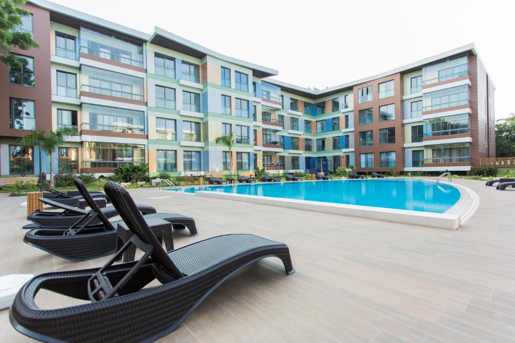 a pool with lounge chairs in front of a building at Accra Luxury Apartments @ Pearl in Accra