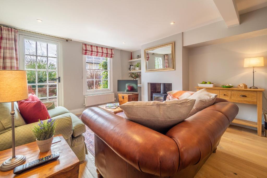 a living room with a brown leather couch at Adorable cottage with a log burner in heavenly village - Constable Lodge in Nayland