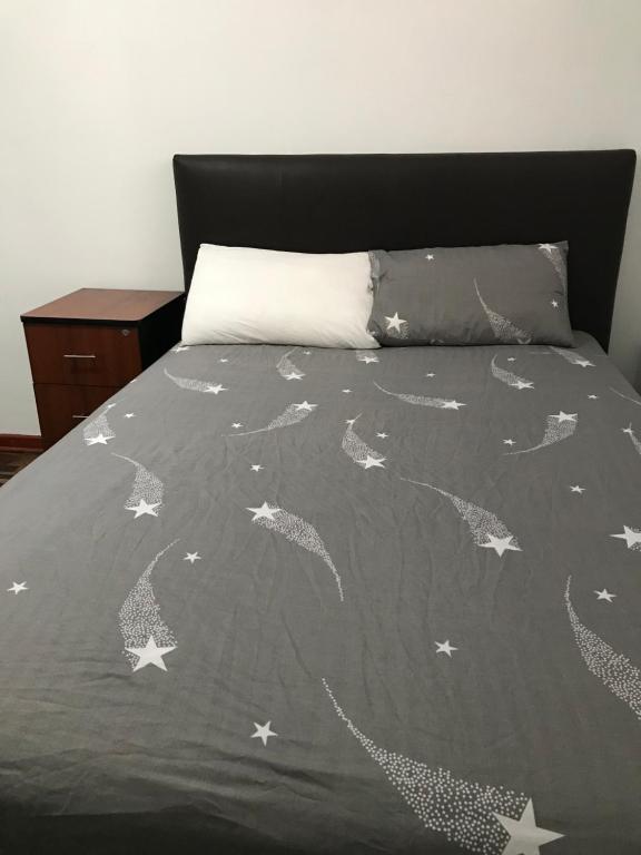 Una cama con un edredón gris con estrellas. en Dormitorio Independiente, en Lima