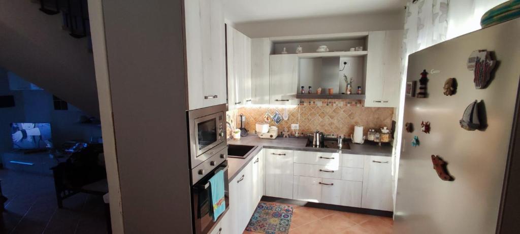a white kitchen with a sink and a refrigerator at Casa Antares in Stintino