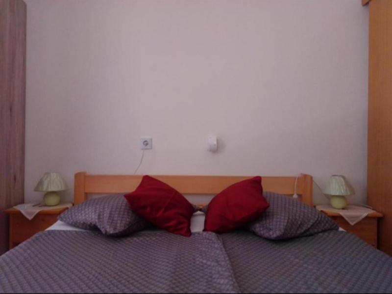 ein Schlafzimmer mit einem Bett mit zwei roten Kissen in der Unterkunft Sant' Elena Room in Bale