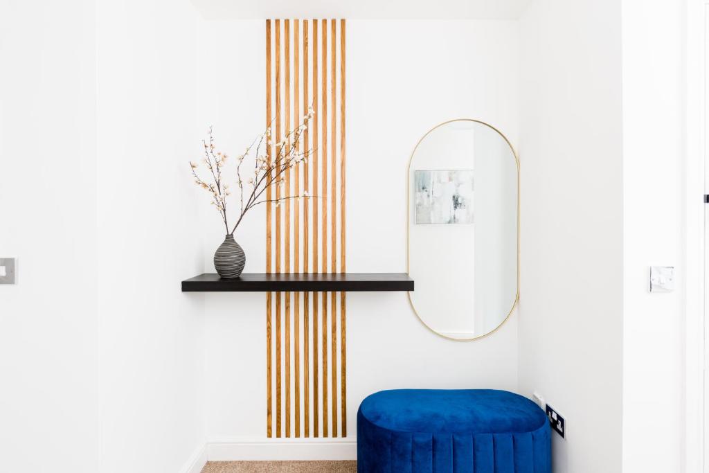 een kamer met een blauwe stoel en een spiegel bij Indigo Apartment in Birmingham