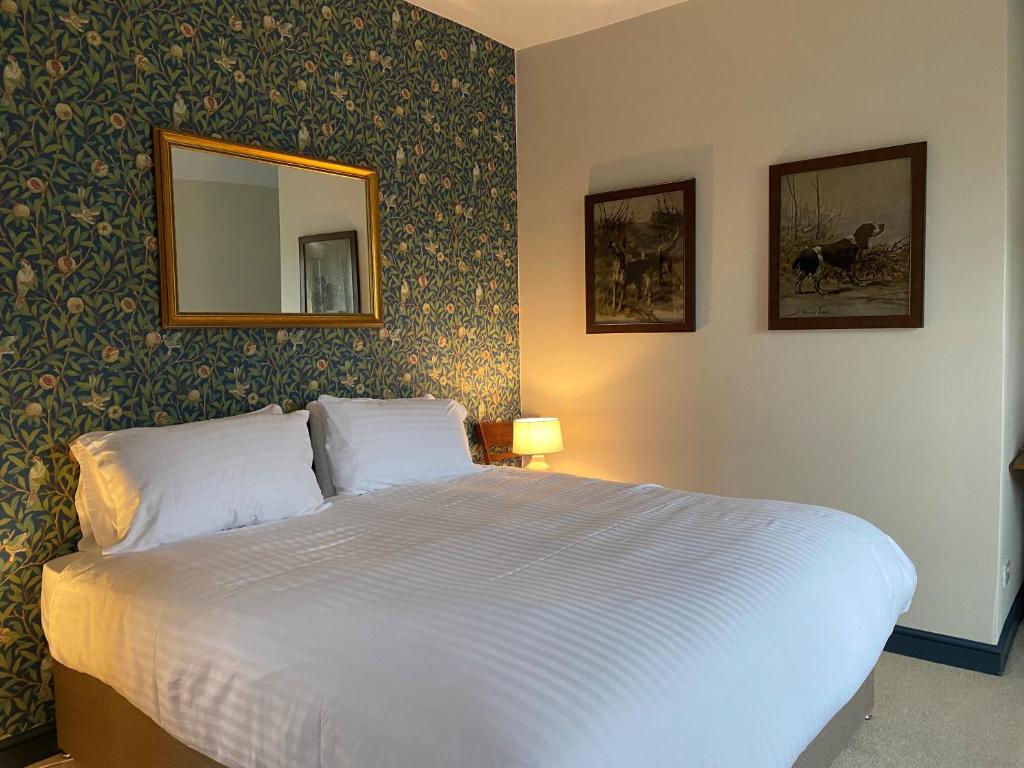 Un dormitorio con una cama blanca con espejo y papel pintado en The Seven Stars en Timsbury