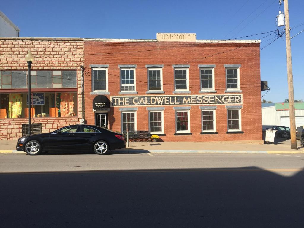 une voiture noire garée devant un bâtiment dans l'établissement Caldwell Messenger Suites, à Caldwell