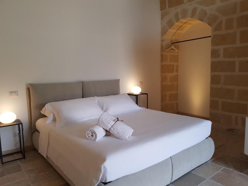 białe łóżko z dwoma rolkami ręczników w obiekcie Residence Masseria Santa Lucia w mieście Matera