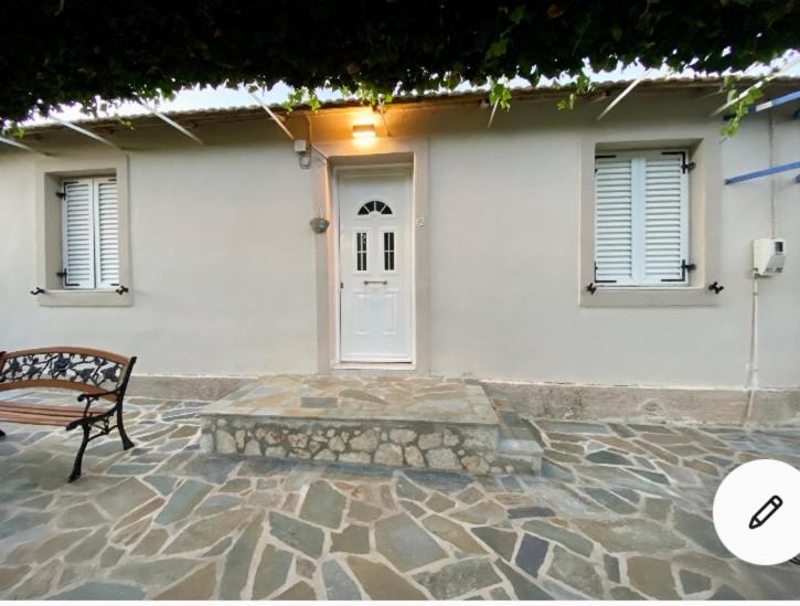 a bench in front of a white building with a door at Dina’s house in Argostoli